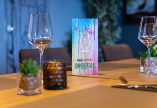 Mesa con menú de cócteles en Camping Waddenzee, Holanda Septentrional, Países Bajos, con copas y decoración.