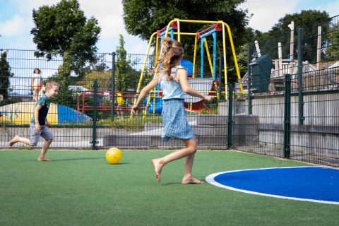 Kinder spielen barfuß Fußball auf einem Spielplatz im Ferienpark Camping Waddenzee in Nordholland, Niederlande.