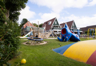 Children playing on a playground with slide, trampoline, and colorful structures at Camping Waddenzee park.