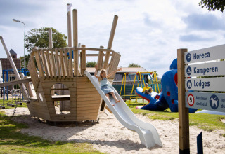 Playground at Camping Waddenzee holiday park featuring a pirate ship slide and children in North-Holland, Netherlands.