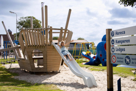 Spielplatz im Ferienpark Camping Waddenzee mit Piratenschiff, Rutsche und Kindern in Nordholland, Niederlande.