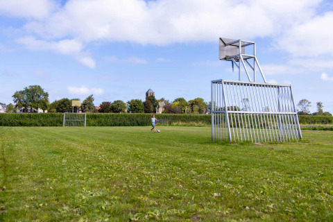 Campo de césped en Camping Waddenzee, Países Bajos, con porterías y aros de baloncesto peculiares.