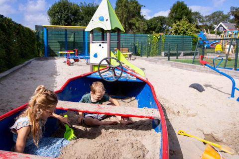 Deux enfants jouent dans un bac à sable en forme de bateau au Camping Waddenzee en Hollande du Nord, Pays-Bas.