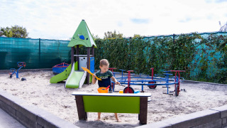 Niño jugando en el arenero del parque infantil en Camping Waddenzee, parque vacacional en Holanda Septentrional.