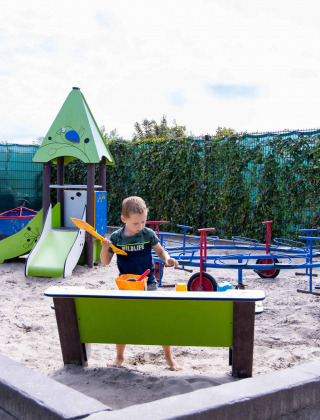 Kind spielt im Sandkasten auf dem Spielplatz von Camping Waddenzee Ferienpark in Nordholland, Holland.