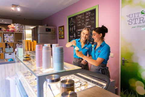 Two women serving ice cream in a modern ice cream shop at Camping Waddenzee, North Holland, Netherlands.