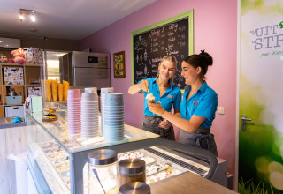 Zwei Frauen servieren Eis in einer modernen Eisdiele im Camping Waddenzee, Nordholland, Niederlande.