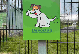 Contenedor verde DepoDog con dibujo de perro alegre en Vakantiepark de Zeeuwse Parel, Zeeland, Países Bajos.