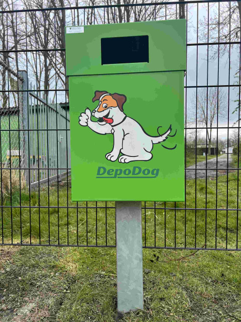 Contenedor verde DepoDog con dibujo de perro alegre en Vakantiepark de Zeeuwse Parel, Zeeland, Países Bajos.