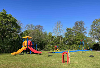 Spielplatz im Vakantiepark de Zeeuwse Parel in Zeeland, Niederlande, mit Rutsche, Schaukeln und Wippen.