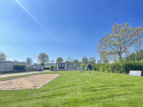 Día soleado en Vakantiepark de Zeeuwse Parel con césped verde, casas móviles y cielo azul claro en Zeeland, Países Bajos.