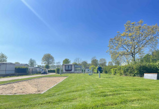 Día soleado en Vakantiepark de Zeeuwse Parel con césped verde, casas móviles y cielo azul claro en Zeeland, Países Bajos.