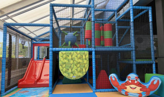 Aire de jeux intérieure au Vakantiepark de Zeeuwse Parel avec toboggan rouge, structures et décor crabe.