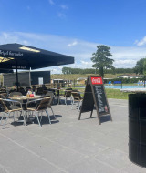 Terraza con mesas y piscina en Vakantiepark de Zeeuwse Parel, un parque vacacional en Zeeland, Países Bajos.