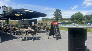 Terraza con mesas y piscina en Vakantiepark de Zeeuwse Parel, un parque vacacional en Zeeland, Países Bajos.