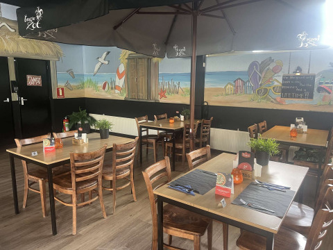 Ristorante interno al Vakantiepark de Zeeuwse Parel, Zelanda, Paesi Bassi, con murale a tema spiaggia.