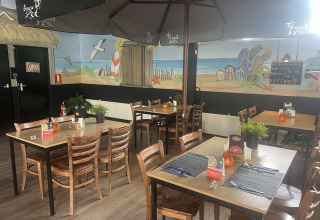 Ristorante interno al Vakantiepark de Zeeuwse Parel, Zelanda, Paesi Bassi, con murale a tema spiaggia.