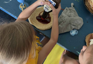 Deux enfants préparent des crêpes à une table avec des ustensiles colorés au parc de vacances Zeeuwse Parel, Zélande.