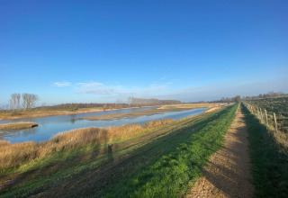 Udsigt over landskabet ved Vakantiepark de Zeeuwse Parel i Zeeland, Holland med sø og sti i morgensol.