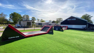 Zona de juegos con obstáculos inflables sobre césped artificial en Vakantiepark de Zeeuwse Parel, Zelanda, Países Bajos.