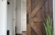 Entrada a una cabaña en De Parel, Vakantiepark de Zeeuwse Parel, con puerta corrediza rústica y planta decorativa.
