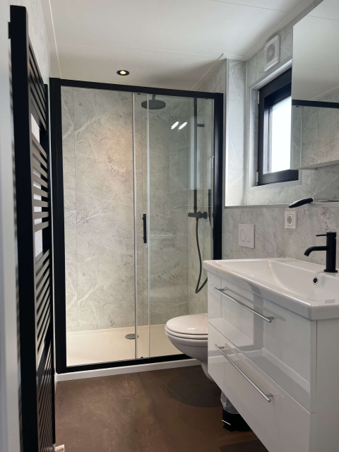 Modern bathroom at De Parel with glass shower, wall-mounted toilet and vanity in Vakantiepark de Zeeuwse Parel.