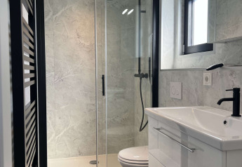 Moderne badeværelse med glasbrusekabine, toilet og hvid vask på De Parel ved Vakantiepark de Zeeuwse Parel.