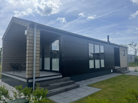 Moderne lodge ved De Parel i Vakantiepark de Zeeuwse Parel, Nederlandene, med veranda og udendørs siddeplads.