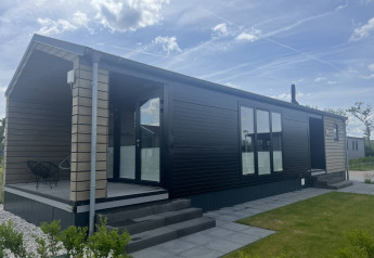 Moderne lodge ved De Parel i Vakantiepark de Zeeuwse Parel, Nederlandene, med veranda og udendørs siddeplads.