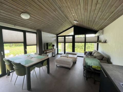 Lodge moderno a De Parel, Vakantiepark de Zeeuwse Parel, Paesi Bassi, con ampio soggiorno e grandi finestre.