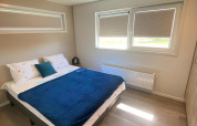 Dormitorio en la cabaña De Schelde del Vakantiepark de Zeeuwse Parel, Países Bajos, con cama y ventanas.