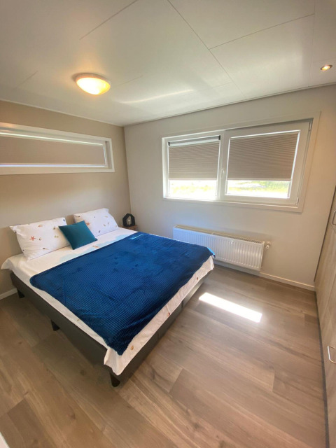 Camera da letto nella De Schelde lodge al Vakantiepark de Zeeuwse Parel, Paesi Bassi, con letto e finestre.