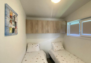 Petite chambre avec deux lits simples, housses thème plage, placards et fenêtre à De Schelde, Zeeuwse Parel.