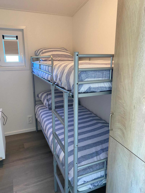 Petite chambre avec lit superposé métallique, fenêtre et déco moderne à De Schelde, Vakantiepark de Zeeuwse Parel.