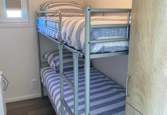 A small room with a metal bunk bed, window, and modern decor at De Schelde in Vakantiepark de Zeeuwse Parel.