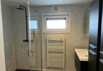 Bagno moderno nel lodge De Zeester presso Vakantiepark de Zeeuwse Parel, Paesi Bassi, con doccia e radiatore.