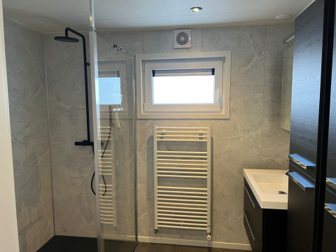 Bagno moderno nel lodge De Zeester presso Vakantiepark de Zeeuwse Parel, Paesi Bassi, con doccia e radiatore.