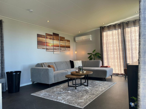 Stijlvolle woonkamer in De Zeester, Vakantiepark de Zeeuwse Parel, met grijze zetel en moderne inrichting.