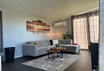 Soggiorno elegante a De Zeester, Vakantiepark de Zeeuwse Parel, con divano grigio e arredo moderno.