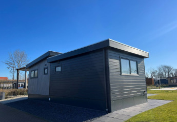 Moderne lodge De Zeester ved Vakantiepark de Zeeuwse Parel i Holland på en solrig dag med blå himmel.