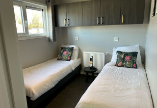 Moderne slaapkamer met twee aparte bedden in De Zeester lodge op Vakantiepark de Zeeuwse Parel, Nederland.