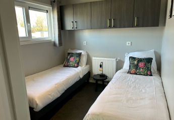 Moderne slaapkamer met twee aparte bedden in De Zeester lodge op Vakantiepark de Zeeuwse Parel, Nederland.
