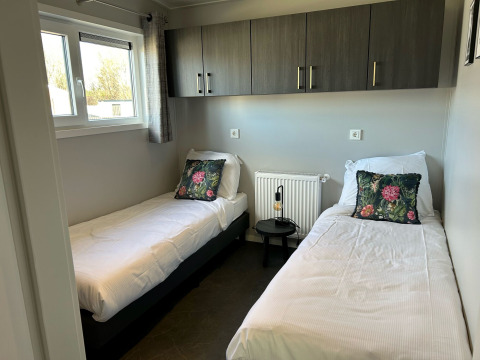 Modernes Schlafzimmer mit zwei Einzelbetten in der De Zeester Lodge, Vakantiepark de Zeeuwse Parel, Niederlande.