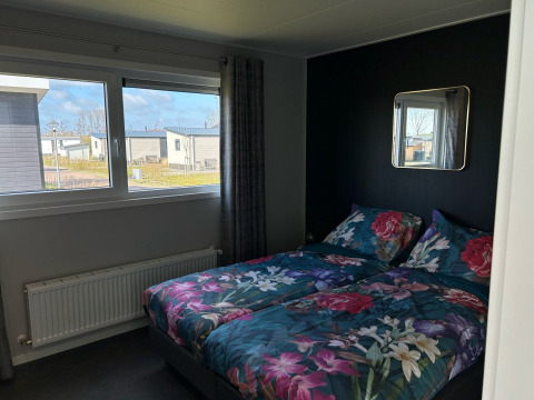 Dormitorio con ropa de cama floral en De Zeester, Vakantiepark de Zeeuwse Parel, Países Bajos.