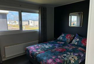 Dormitorio con ropa de cama floral en De Zeester, Vakantiepark de Zeeuwse Parel, Países Bajos.