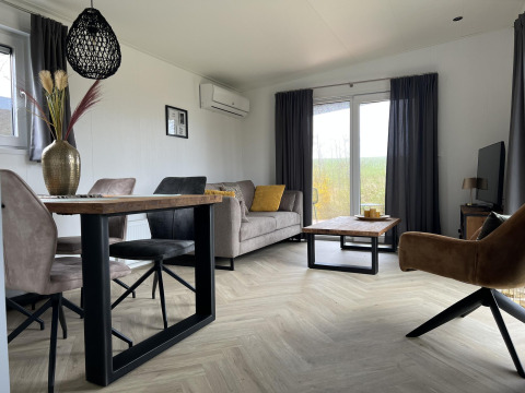 Salón moderno en el lodge Dijkzicht, Vakantiepark de Zeeuwse Parel, Países Bajos, con luz natural y decoración elegante.