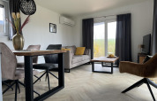 Moderne woonkamer in lodge Dijkzicht in Vakantiepark de Zeeuwse Parel, Nederland, met stijlvolle inrichting en raam.