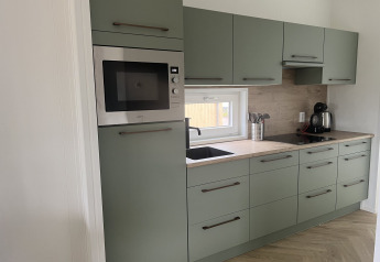 Moderne keuken in lodge Dijkzicht op Vakantiepark de Zeeuwse Parel, Nederland, met groene kasten.