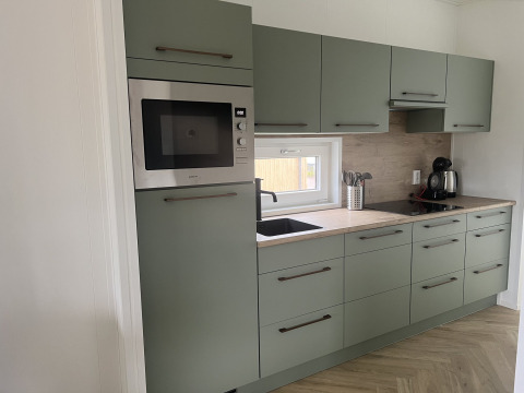 Moderne Küche in der Dijkzicht-Lodge im Vakantiepark de Zeeuwse Parel, Niederlande, mit grünen Schränken.