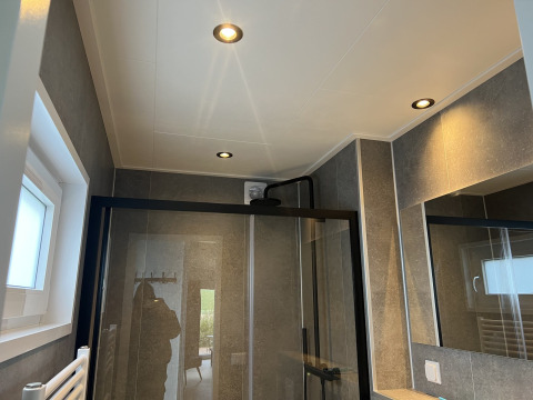 Baño moderno con ducha, espejo y detalles en negro en la Lodge Dijkzicht, parque Zeeuwse Parel, Países Bajos.